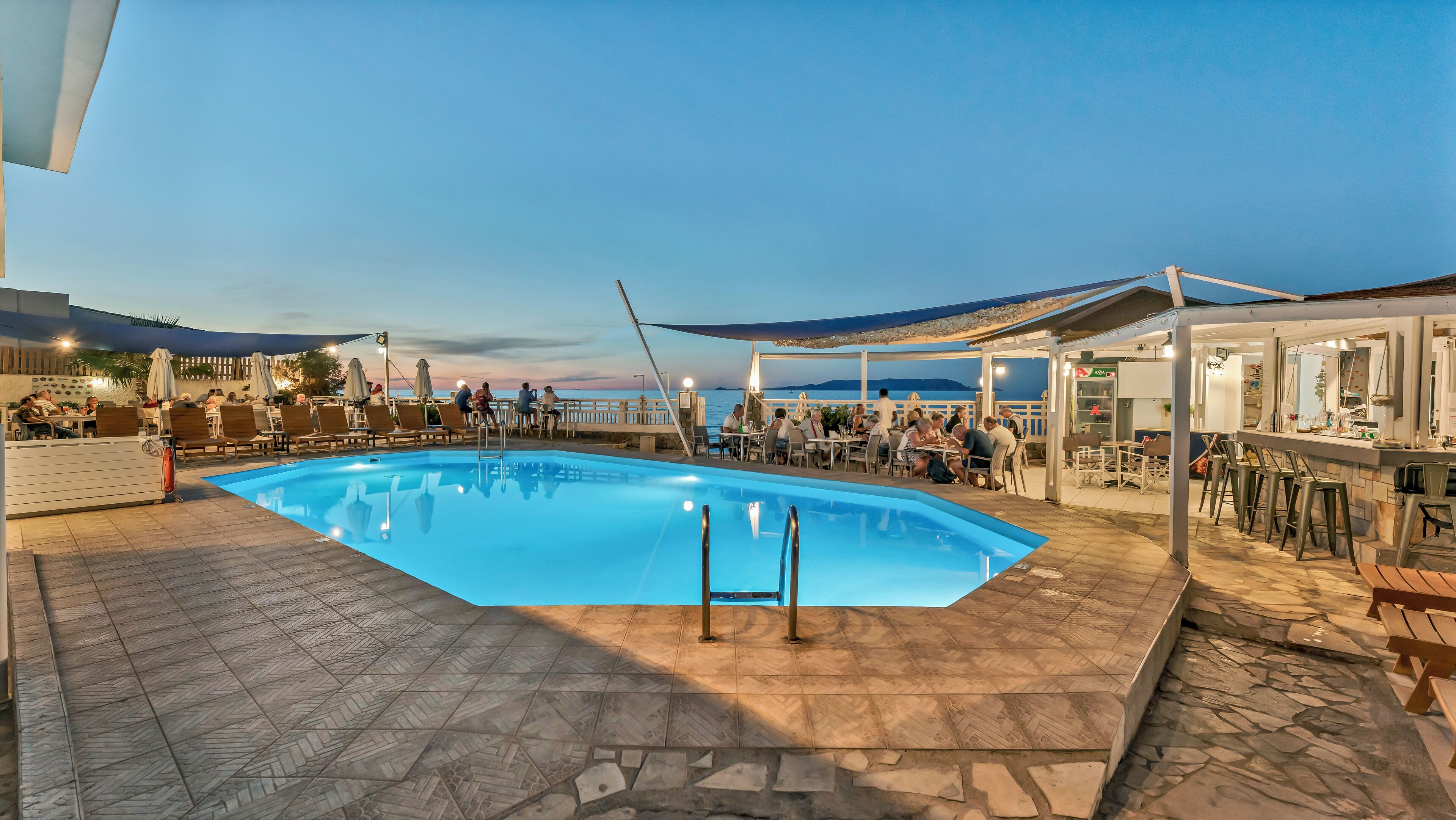 A poolside area with a pool, outdoor seating, and a bar area.