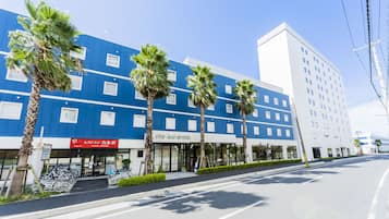 Experience the CIS Ray Hotel's sleek, modern design, set amidst lush palm trees in a vibrant urban setting.