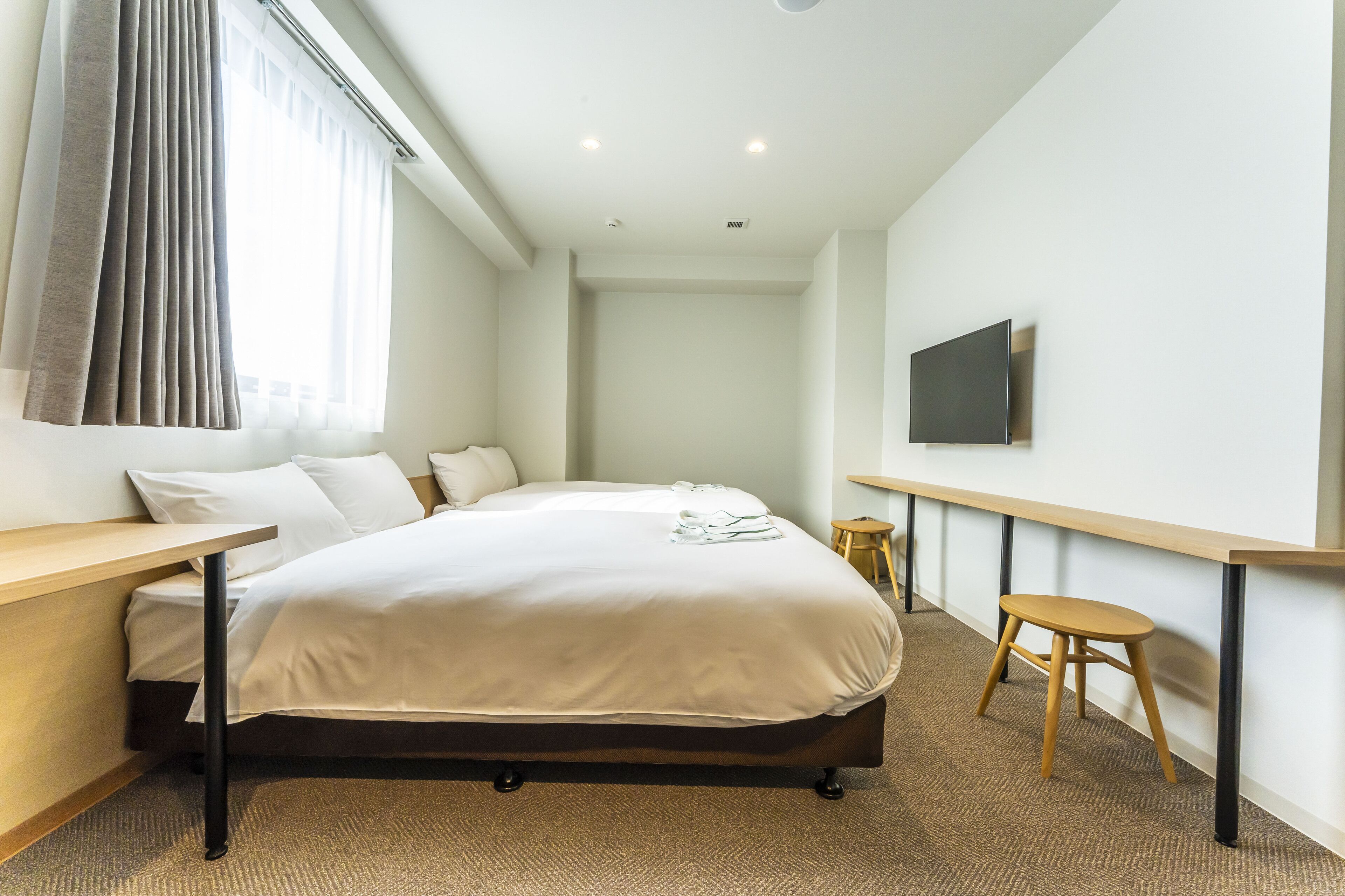 Une chambre d’hôtel équipée d’un lit, d’un bureau, d’une chaise, d’une télévision et d’une fenêtre avec des rideaux.