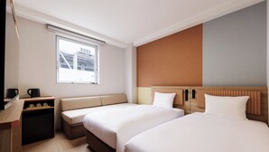 A hotel room with two beds, a sofa, a desk with a coffee maker, and a window with a view of buildings. - CVS Bay Hotel (Ichikawa)