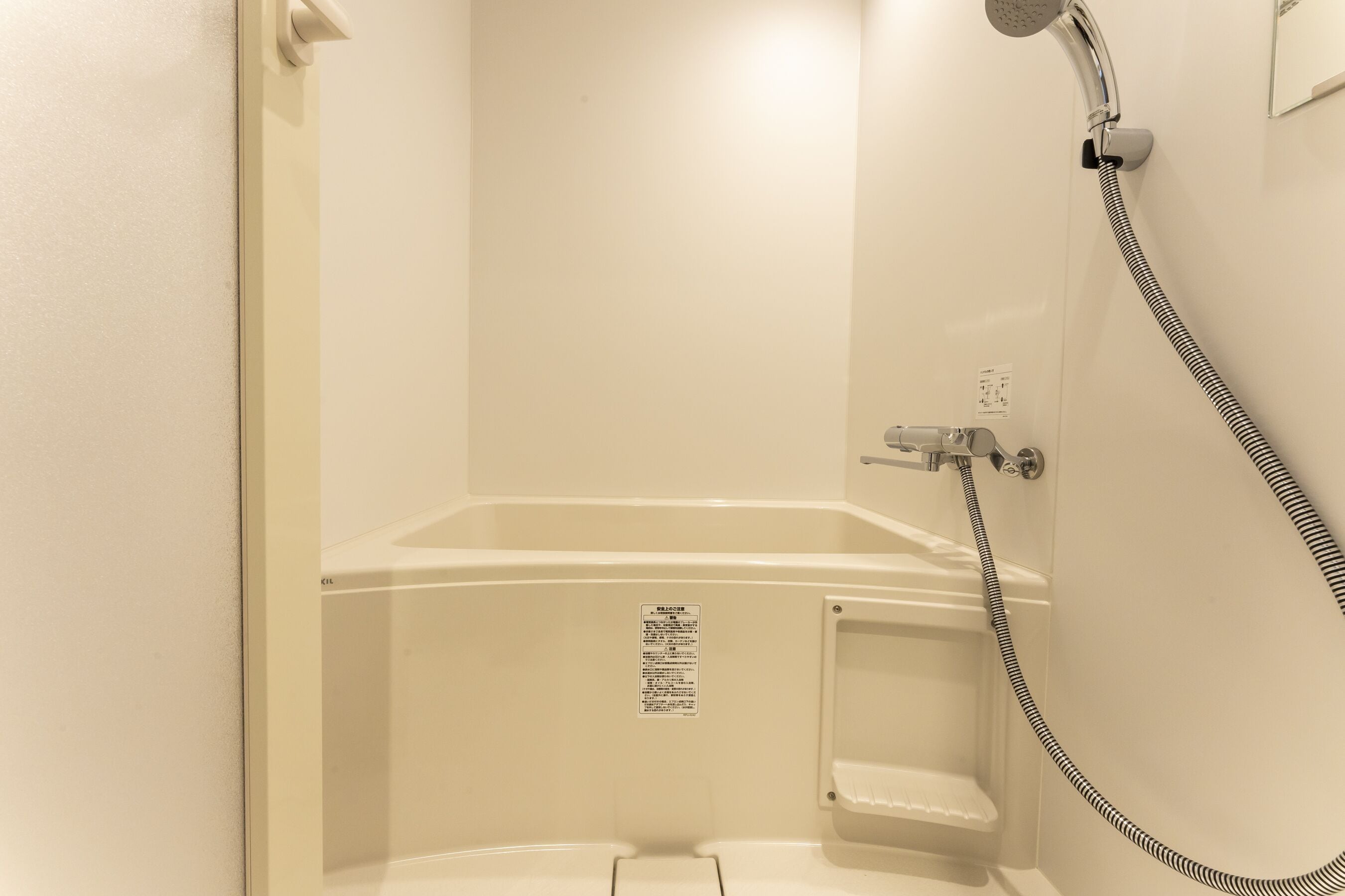 A small, enclosed shower area with a handheld showerhead and a control knob.