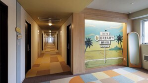 A hotel corridor with directional signs, a colorful carpet, and a mural advertising the Tokyo Dreamy Bay Hotel. - CVS Bay Hotel (Ichikawa)