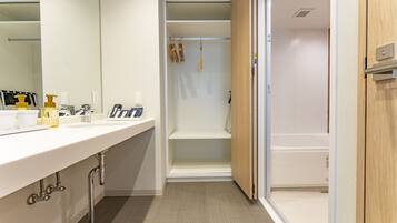 Un baño moderno con un tocador blanco, una zona de ducha y una puerta de madera.