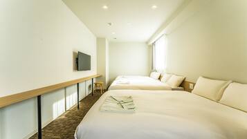 A hotel room with two beds, a flat-screen TV mounted on the wall, and a wooden bench.