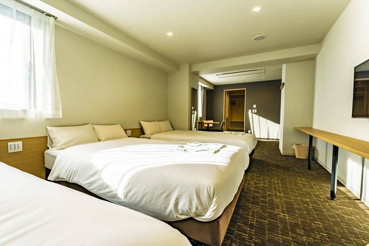 A hotel room with two beds, a wooden headboard, a small table, and a mirror on the wall.