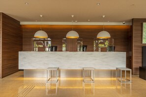 A reception area with a marble counter, three pendant lights, and a wooden wall. - CVS Bay Hotel (Ichikawa)