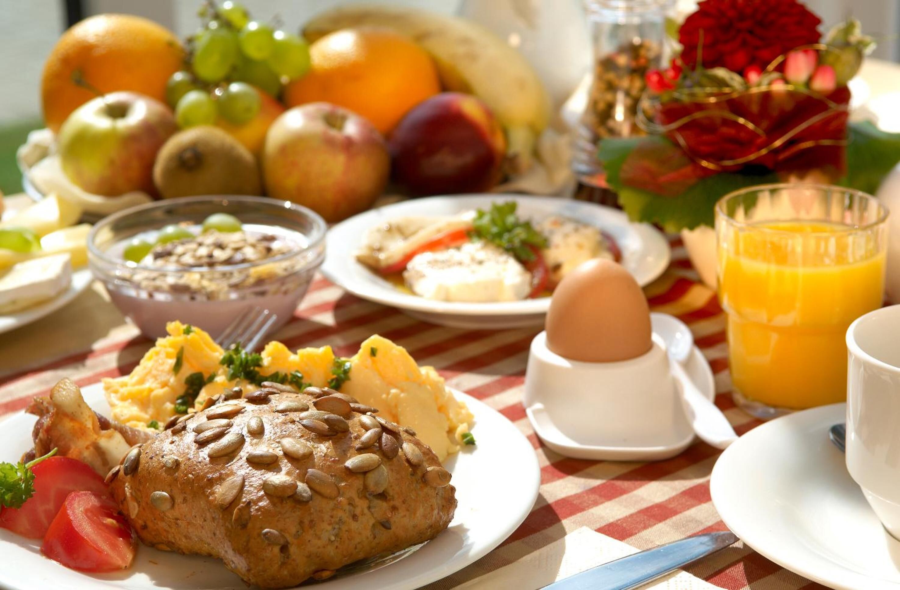Una mesa de desayuno con diversos alimentos, como huevos, tostadas y fruta.