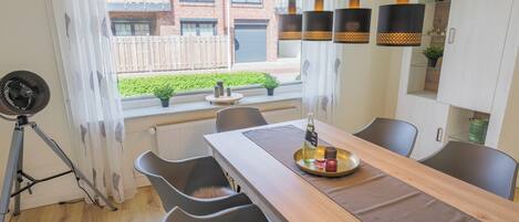 A modern kitchen with a wooden table, grey chairs, and pendant lights.