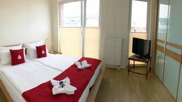 A hotel room with a bed, a television, and a view of the outside.