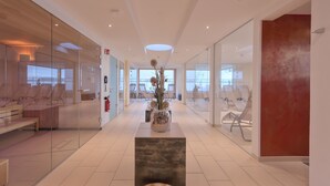 Un moderno vestíbulo de hotel con paredes de vidrio, una exhibición central de plantas y un diseño limpio y minimalista.