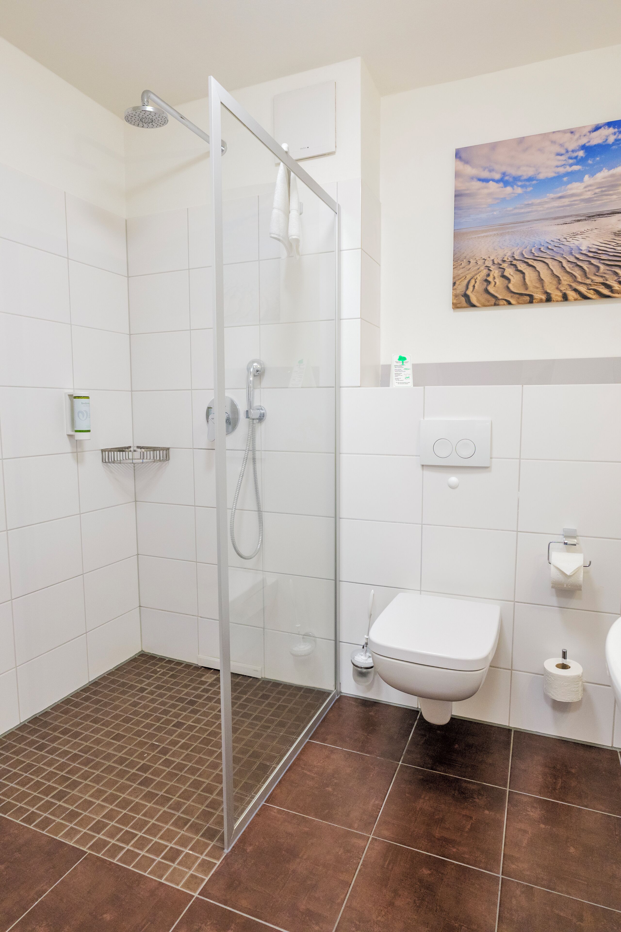 A modern bathroom with a glass shower enclosure, a toilet, and a sink.