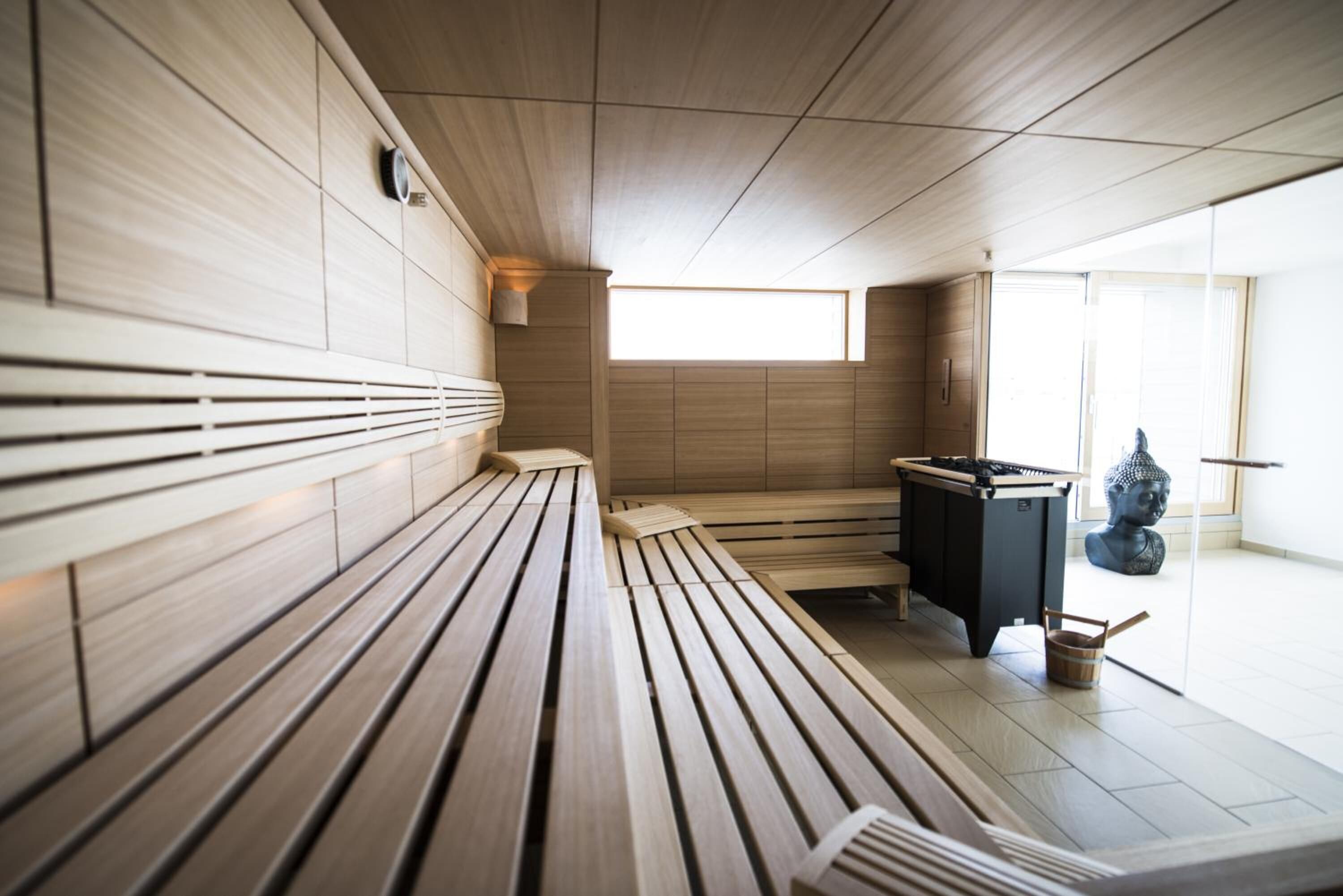 Una sala de sauna con bancos de madera, una camilla de sauna y una estatua.