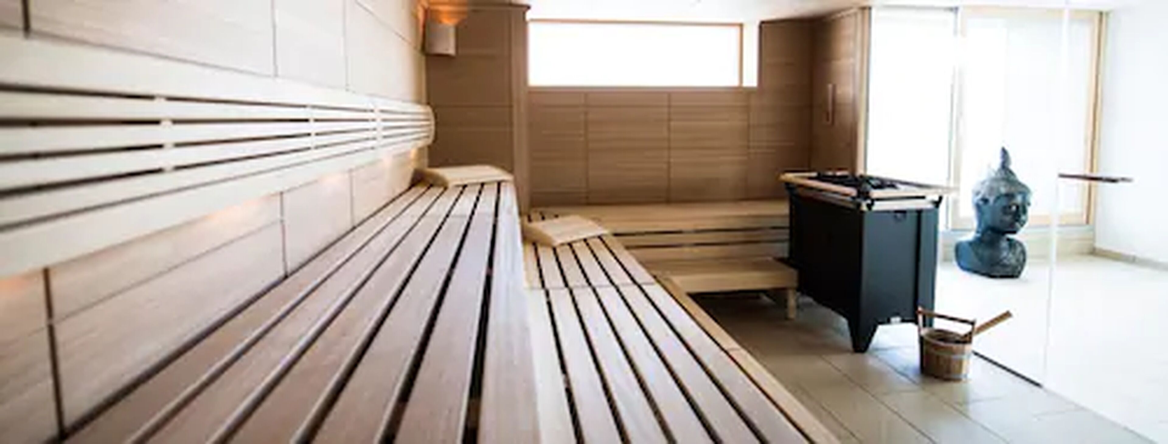 A sauna with wooden benches and a small table with a statue.