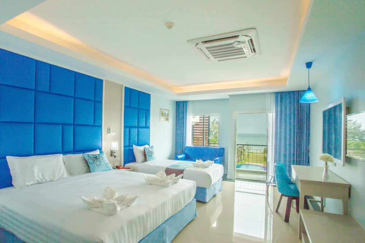 Una habitación de hotel con una cama grande, un escritorio y un balcón con cortinas azules.