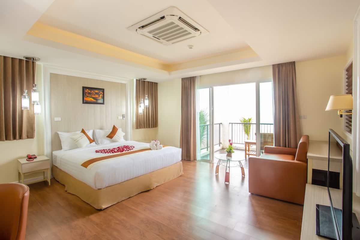 Habitación de hotel con una cama grande, televisor, sofá y balcón con vistas.