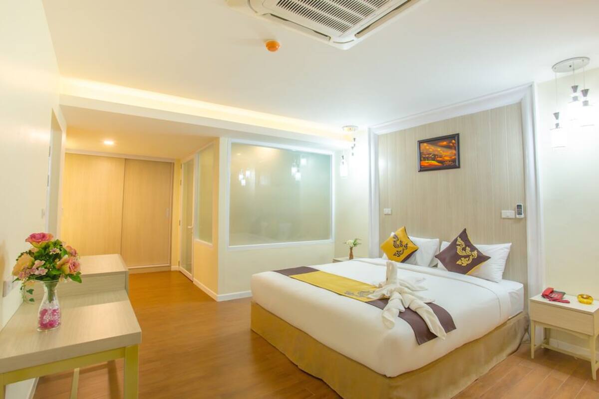Una habitación de hotel con cama, mesita de noche y ventana con vidrio esmerilado.