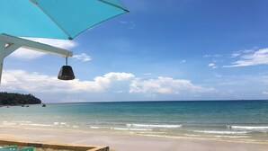 A beach with a clear sky, a turquoise umbrella, and calm sea. - Ma Maison Phuket (Choeng Thale)