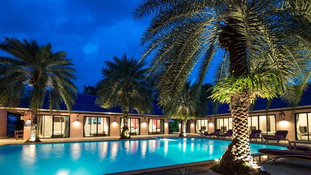 A swimming pool surrounded by palm trees and a building with multiple rooms. - Ma Maison Phuket (Choeng Thale)