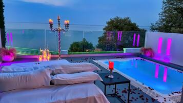 Relax by the pool surrounded by steps leading down to the water's edge, with a table and candle nearby.