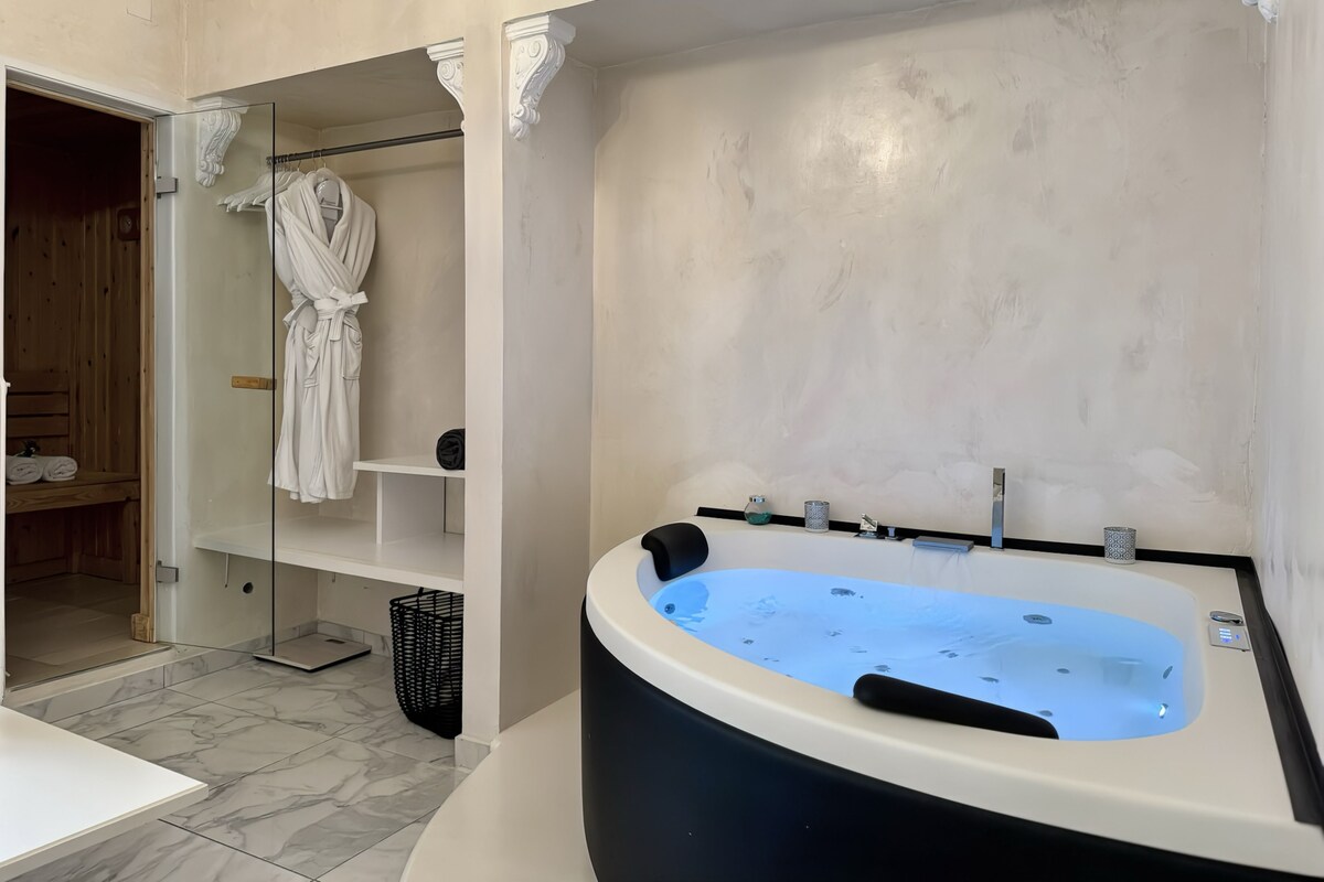 A bathroom with a large bathtub, a glass shower enclosure, and a wooden sauna area.