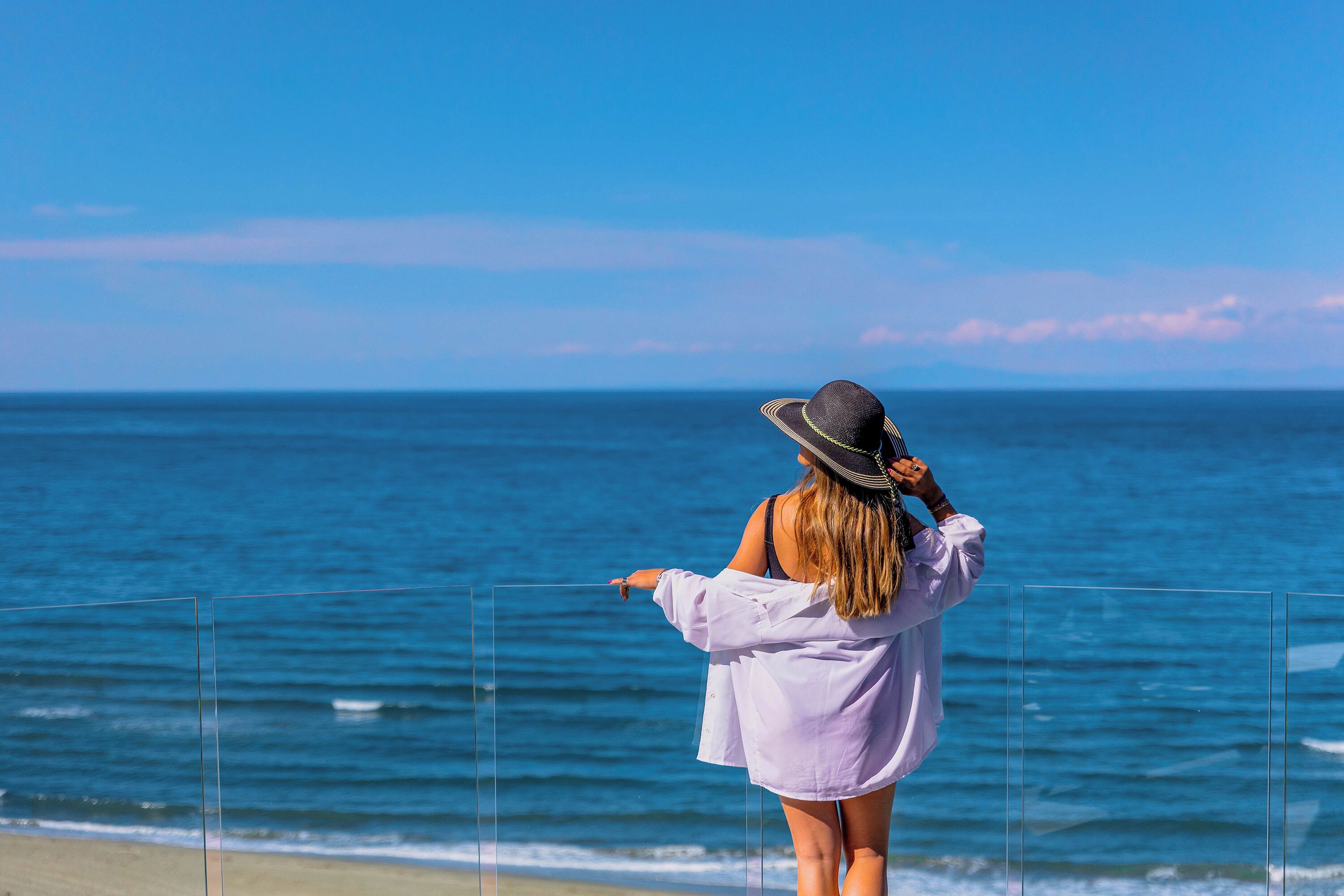 A person standing on a beach, facing the ocean.