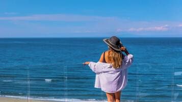 A person standing on a beach, facing the ocean.