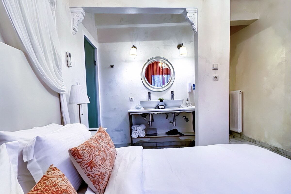A hotel room with a large bed, a vanity with a mirror, and a radiator.