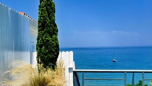 A hot tub with a clear view of the ocean and a sailboat in the distance. - Panorama Suites & Spa (Agia)