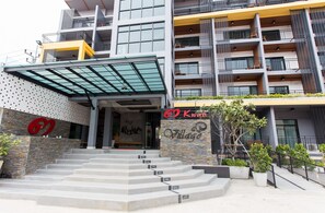 A multi-story building with a modern design, featuring a glass entrance canopy, a stone facade, and a sign that reads "Kwan Village". - 3 Kwan Village (Chonburi)