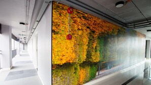 A corridor with a large wall mural depicting autumn foliage, a polished floor, and a ceiling with visible ductwork and lighting fixtures. - 3 Kwan Village (Chonburi)
