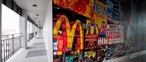 Um corredor com um grande anúncio do McDonald's na parede, chão de azulejos e um corrimão à esquerda.