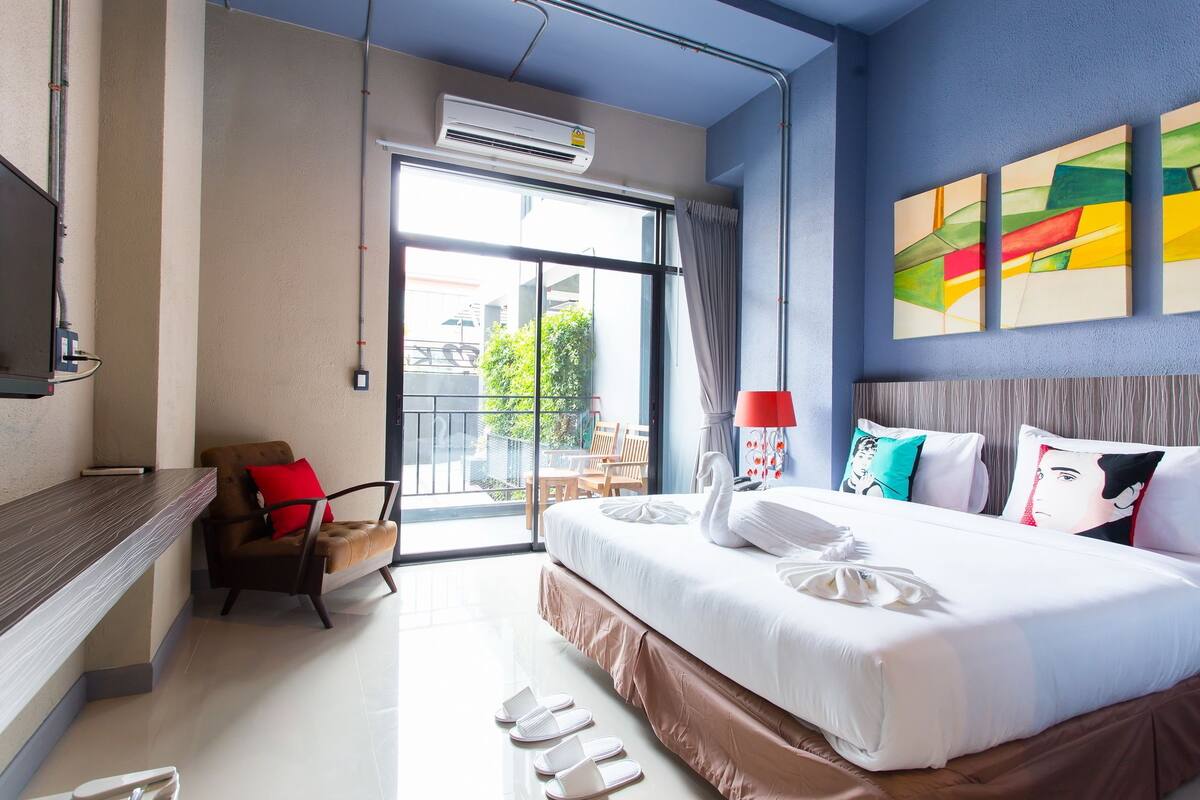 A hotel room with a bed, a desk, a chair, and a balcony with a view.