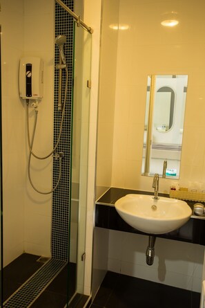 A bathroom with a glass-enclosed shower, a white sink, and a mirror above it. - 3 Kwan Village (Chonburi)