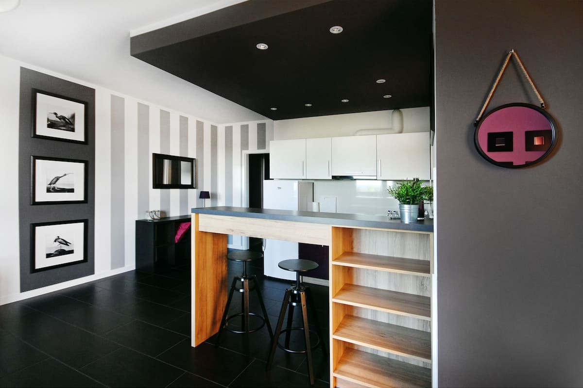 A modern kitchen with a central island, bar stools, and a decorative mirror.