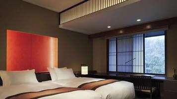 A modern hotel room with a large bed, a desk, and a window with a view of trees.