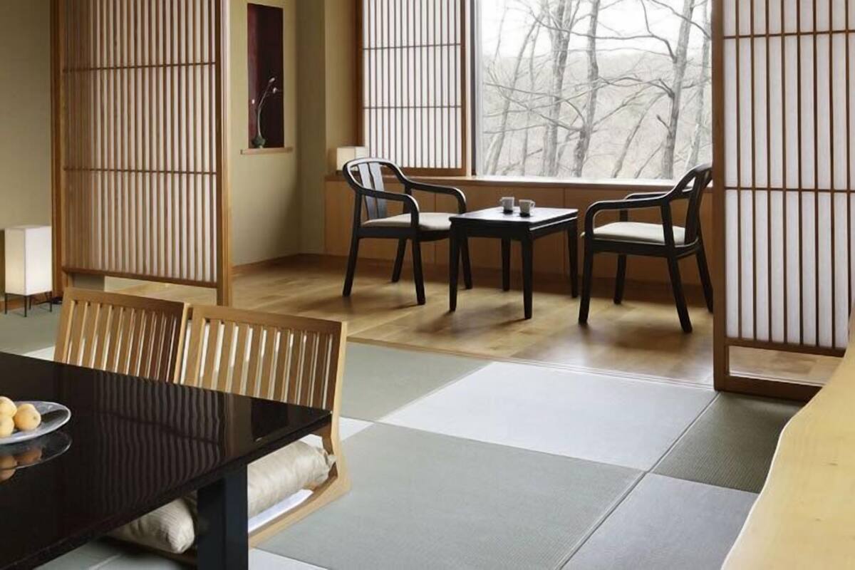 A traditional Japanese room with tatami flooring, a low table with cushions, and sliding shoji screens.