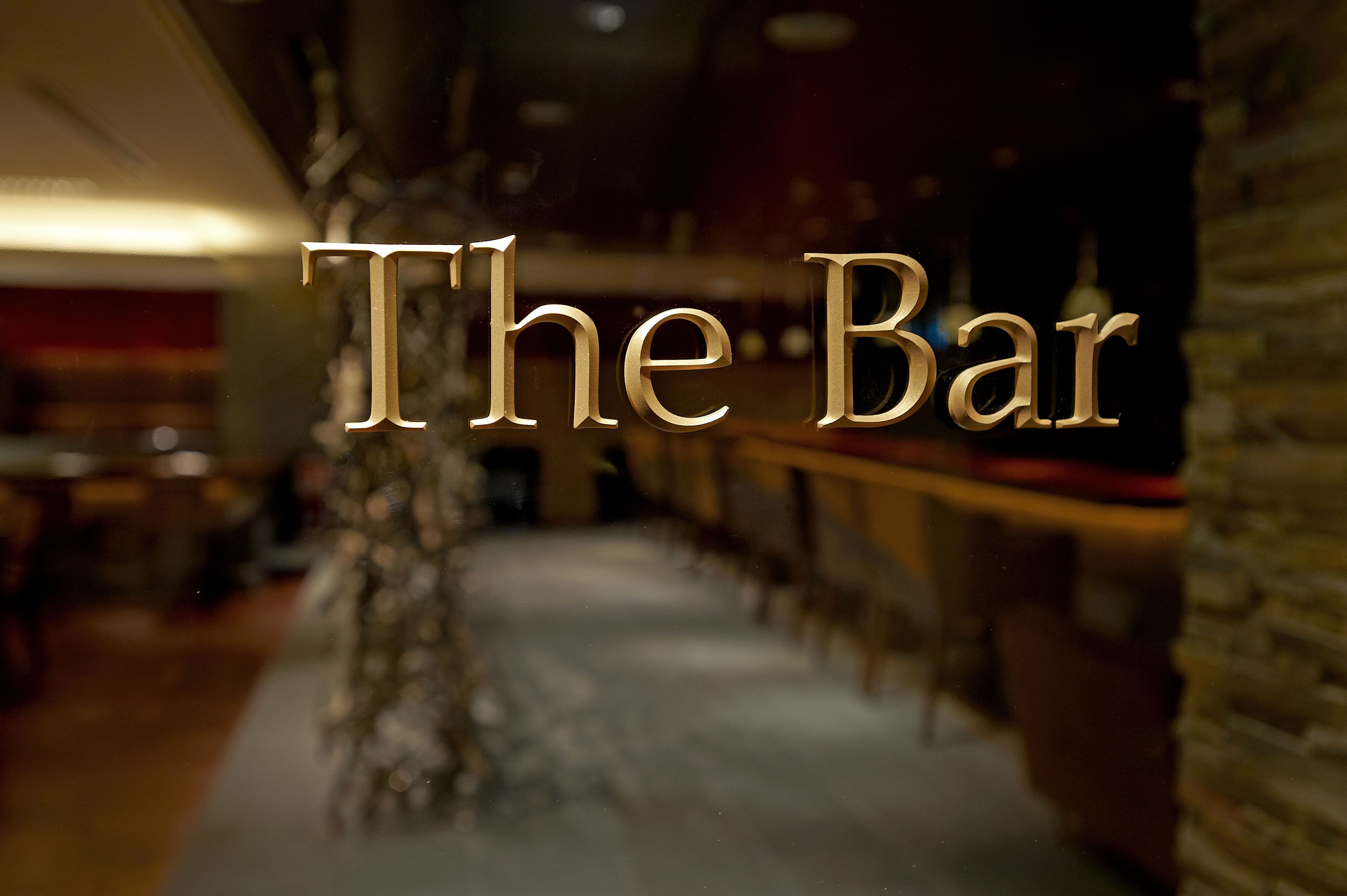 A bar area with a wooden bar counter and a stone wall.