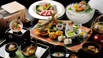 Eine Auswahl traditioneller japanischer Gerichte auf einem Tisch, darunter Sushi, Sashimi und weitere Köstlichkeiten, zusammen mit Stäbchen und kleinen Schalen.