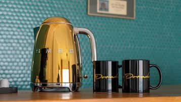 Uma bancada de cozinha com uma cafeteira, duas canecas e um prêmio emoldurado na parede.