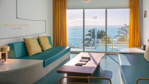 A room with a sofa, a table, and a view of the ocean.