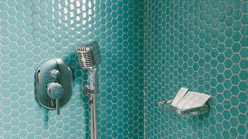 A bathroom with a teal hexagonal tile pattern, a vintage-style showerhead, and a soap dish.