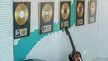 Un mur orné de pochettes de disques encadrées et d’une guitare.