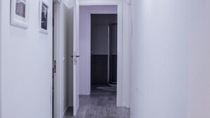 A narrow hallway with white walls, grey wooden flooring, and recessed ceiling lights. - Domus Raffaello suite in Rome (Rome)