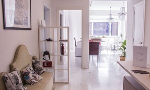 A modern living room with a sofa, a glass partition, and a dining area with a table and chairs. - Domus Raffaello suite in Rome (Rome)