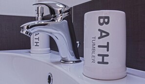 A bathroom sink with a modern faucet and a white soap dispenser labeled "BATH TUMBLER". - Domus Raffaello suite in Rome (Rome)