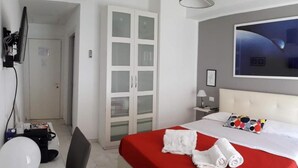 A hotel room with a bed, a desk, a chair, a wardrobe, a television, and a television stand. - Domus Raffaello suite in Rome (Rome)