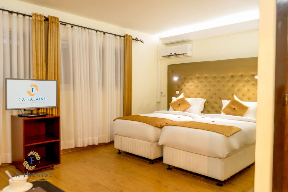 A hotel room with two beds, a TV, and a wardrobe.