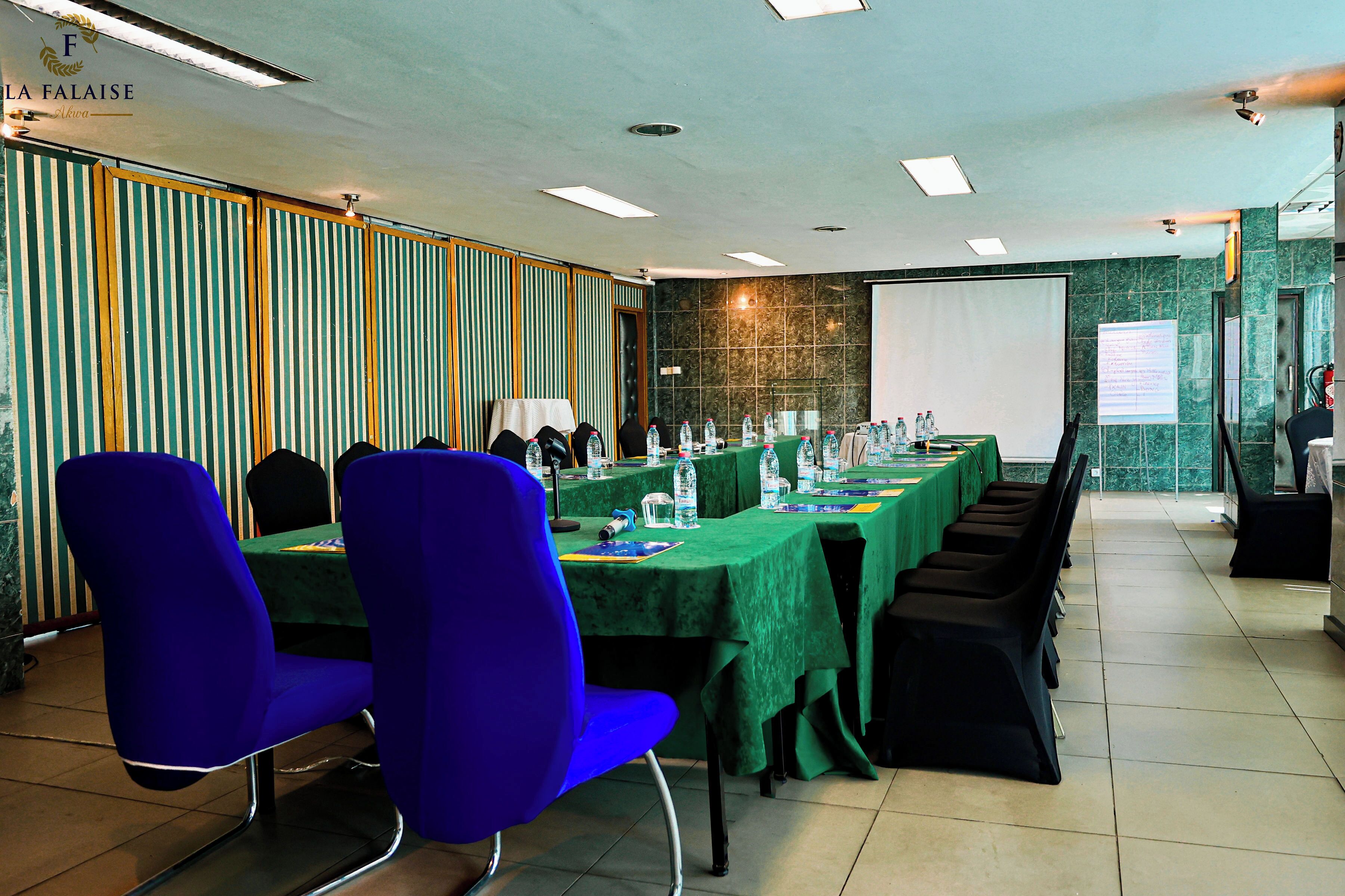 A conference room with a long table, chairs, and a projector screen.