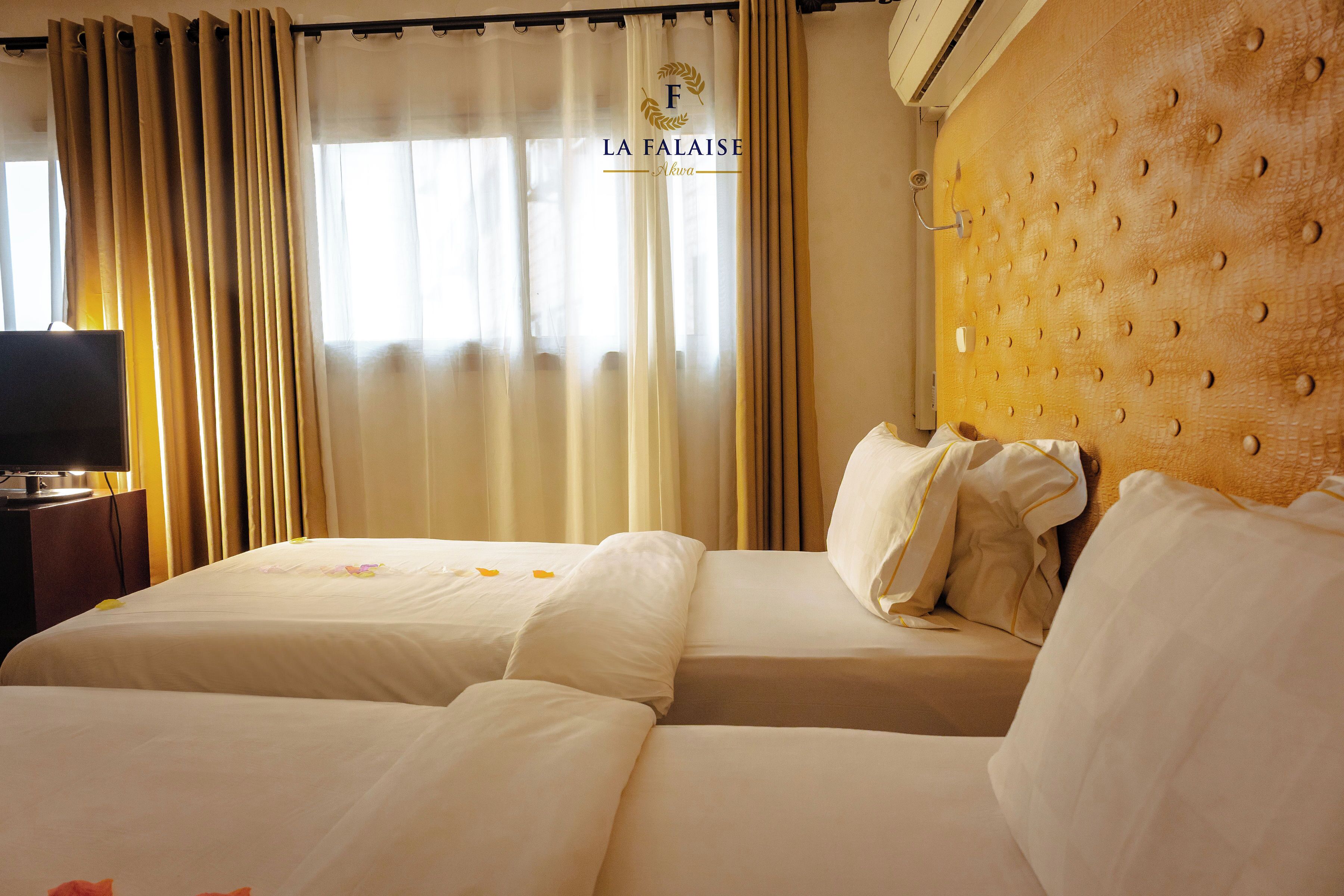 Una habitación de hotel con cama, cortinas y televisor.