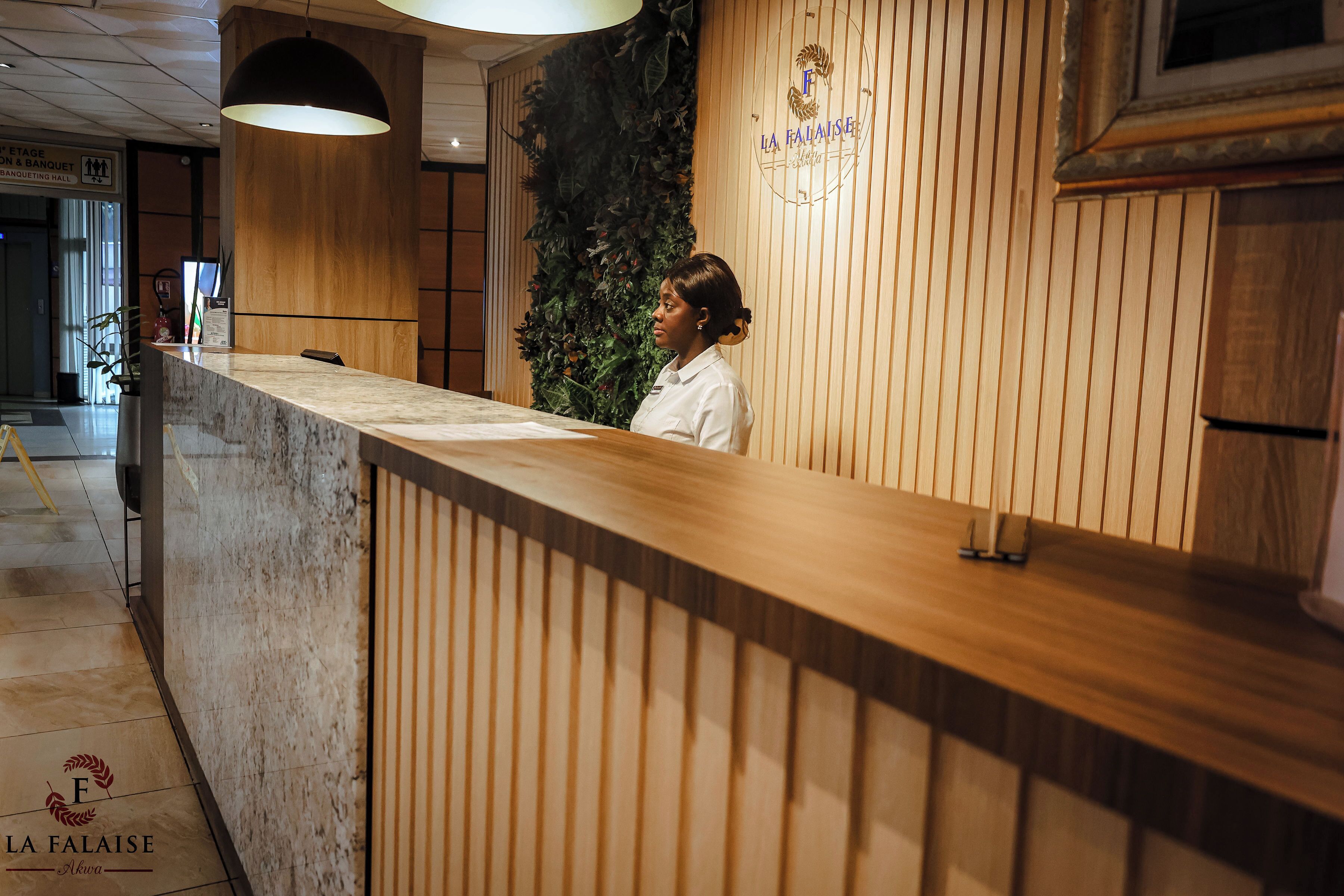 Taulell de recepció amb acabat de fusta, un logotip a la paret i un senyal que indica l'ubicació de la sala de banquet.